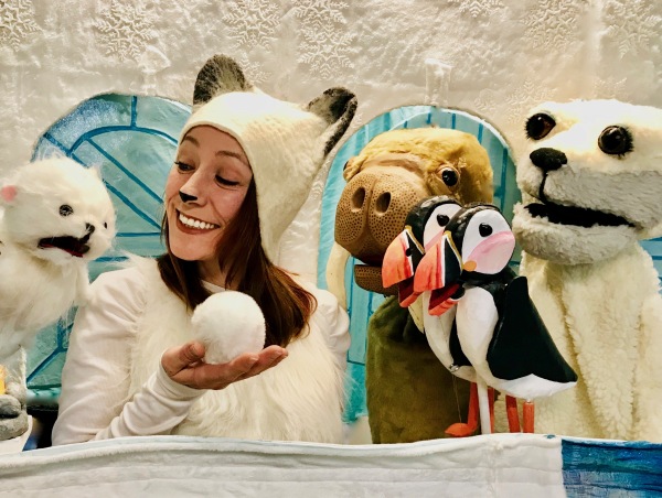 woman in white clothing holding snowball with animal puppets