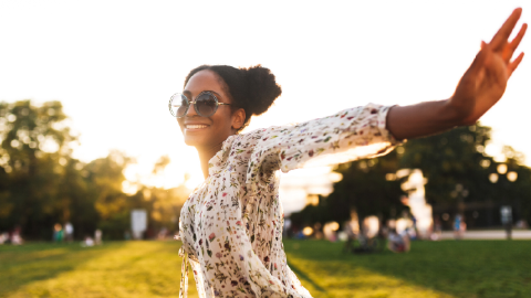 woman outdoors, smiling with outstretched arm